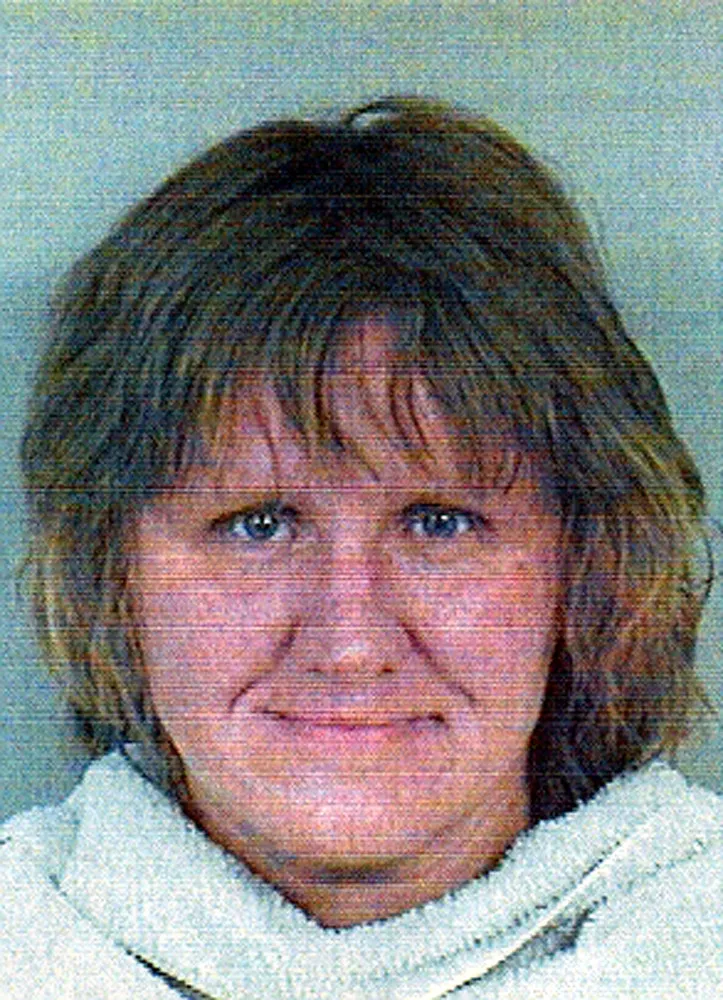 Foto de Dena Schlosser durante seu julgamento, com expressão ausente.