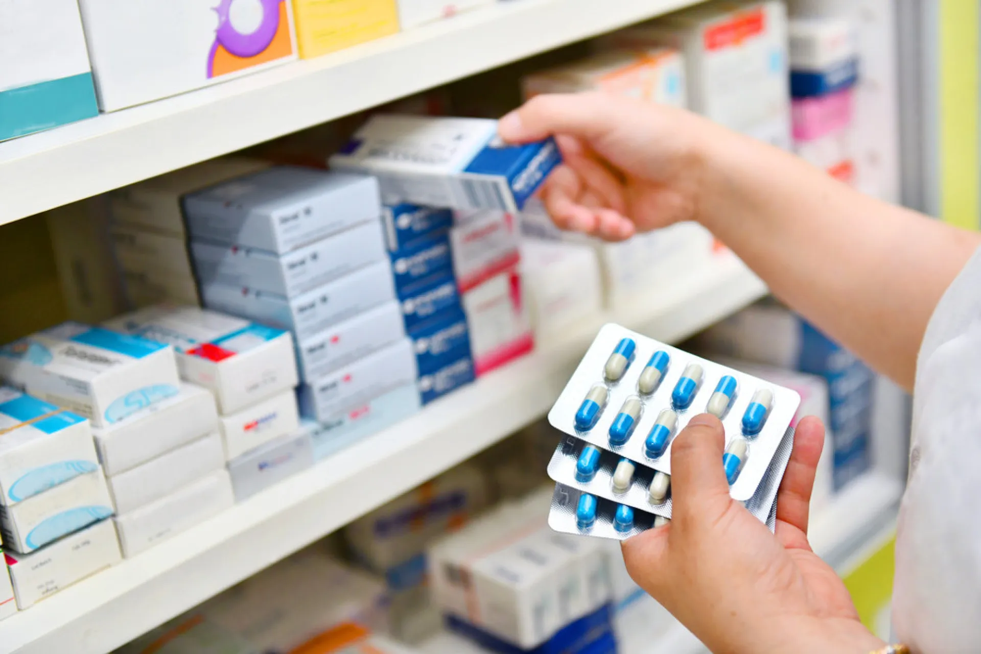 Uma mão segurando um hambúrguer em frente a uma pilha de contas médicas e dinheiro.