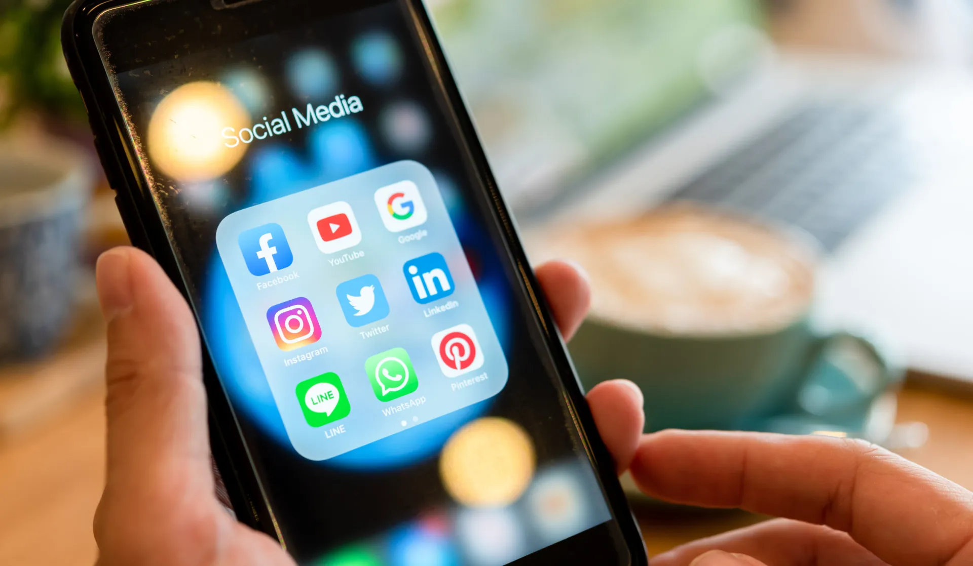Uma pessoa usando um smartphone com ícones de redes sociais flutuando ao redor.