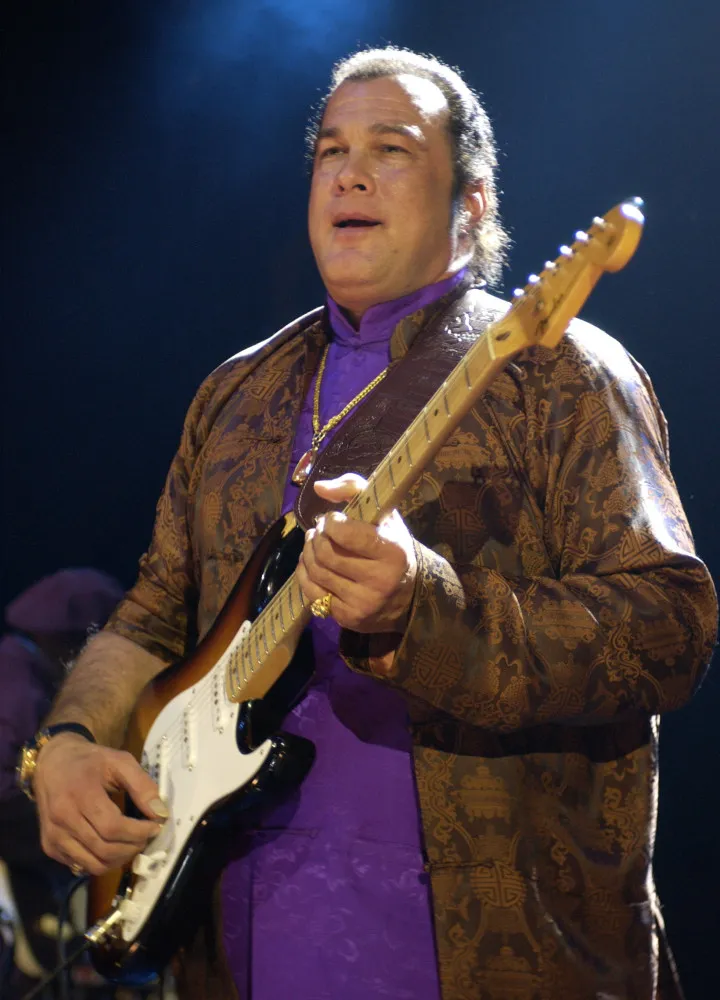 Steven Seagal tocando guitarra com sua banda, Thunderbox, durante um show.