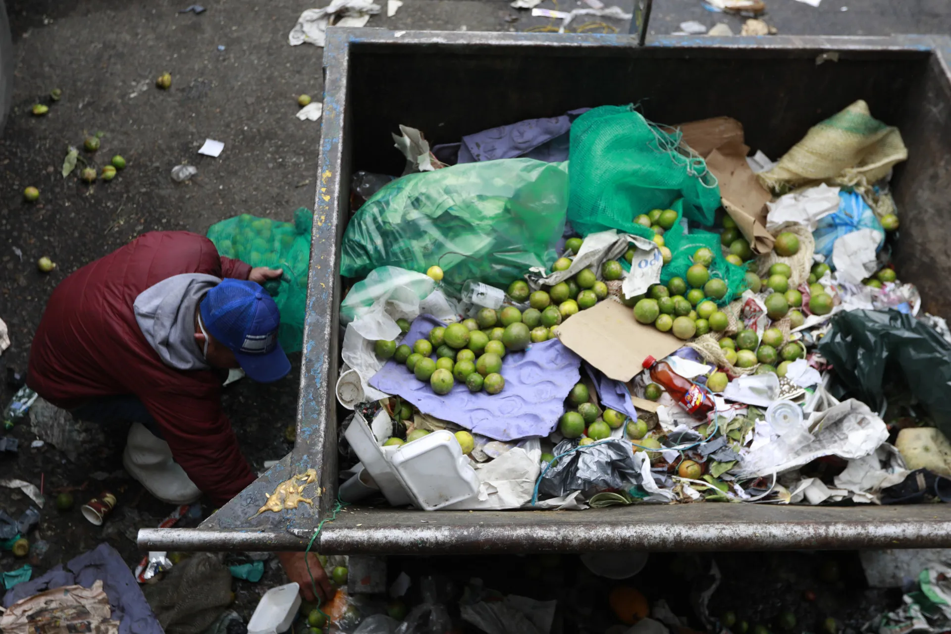 Saco de lixo cheio de alimentos descartados, como pães e vegetais.