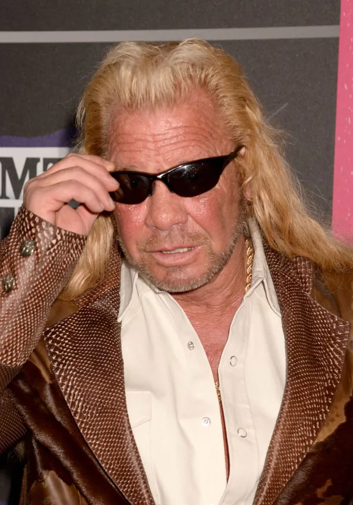 Duane Chapman com seu visual característico, óculos escuros e cabelos longos.