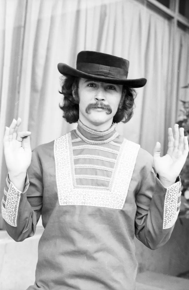 O cantor e compositor David Crosby tocando violão no palco.