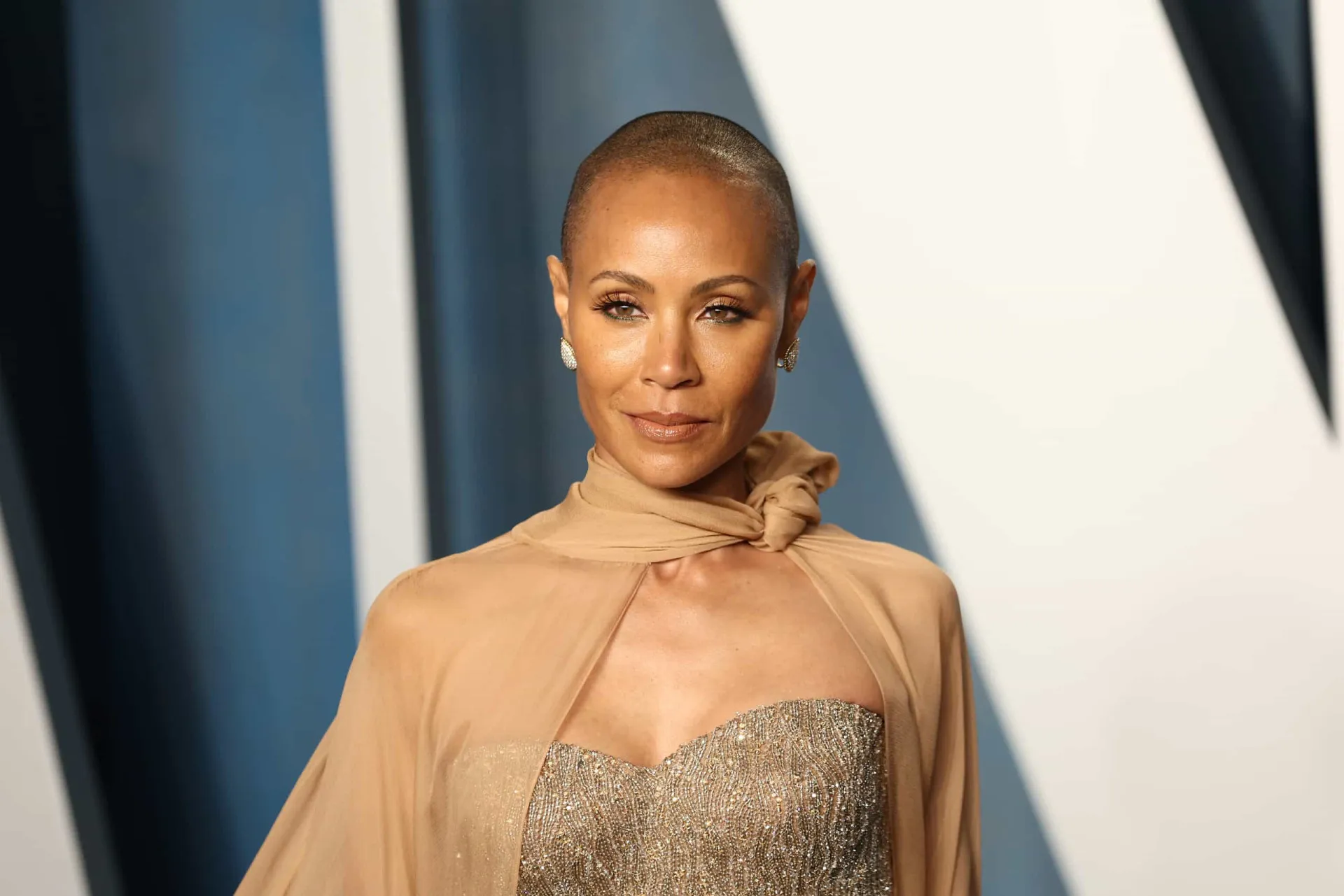 Jada Pinkett Smith com a cabeça raspada em um evento, exibindo sua beleza e confiança.