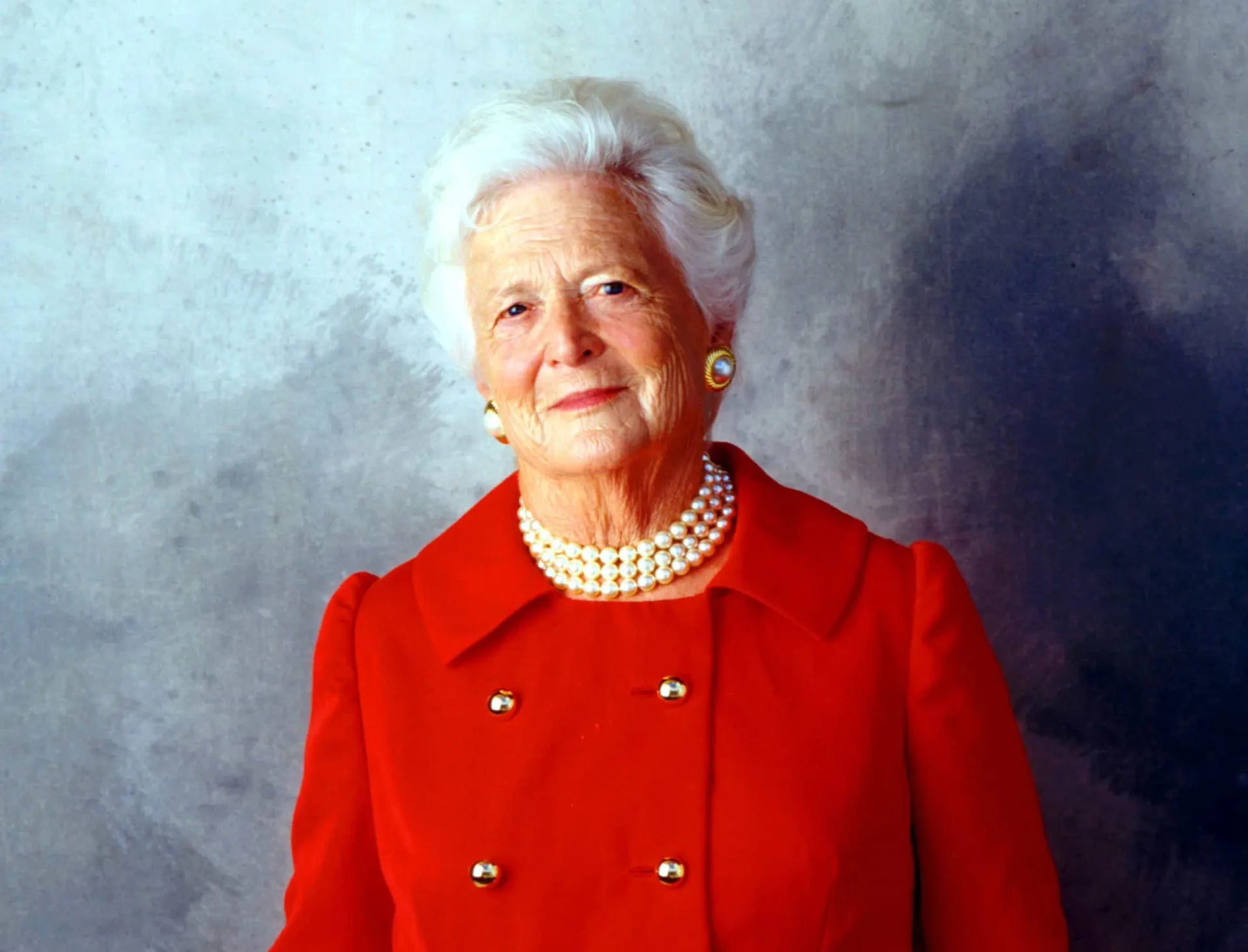 A primeira-dama Barbara Bush com seu colar de pérolas característico e um sorriso caloroso.