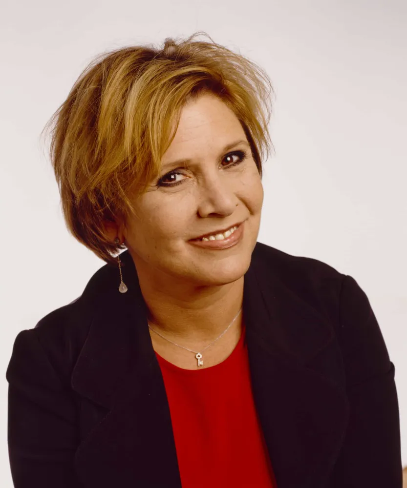 Carrie Fisher em um evento, com sua expressão icônica e forte presença.