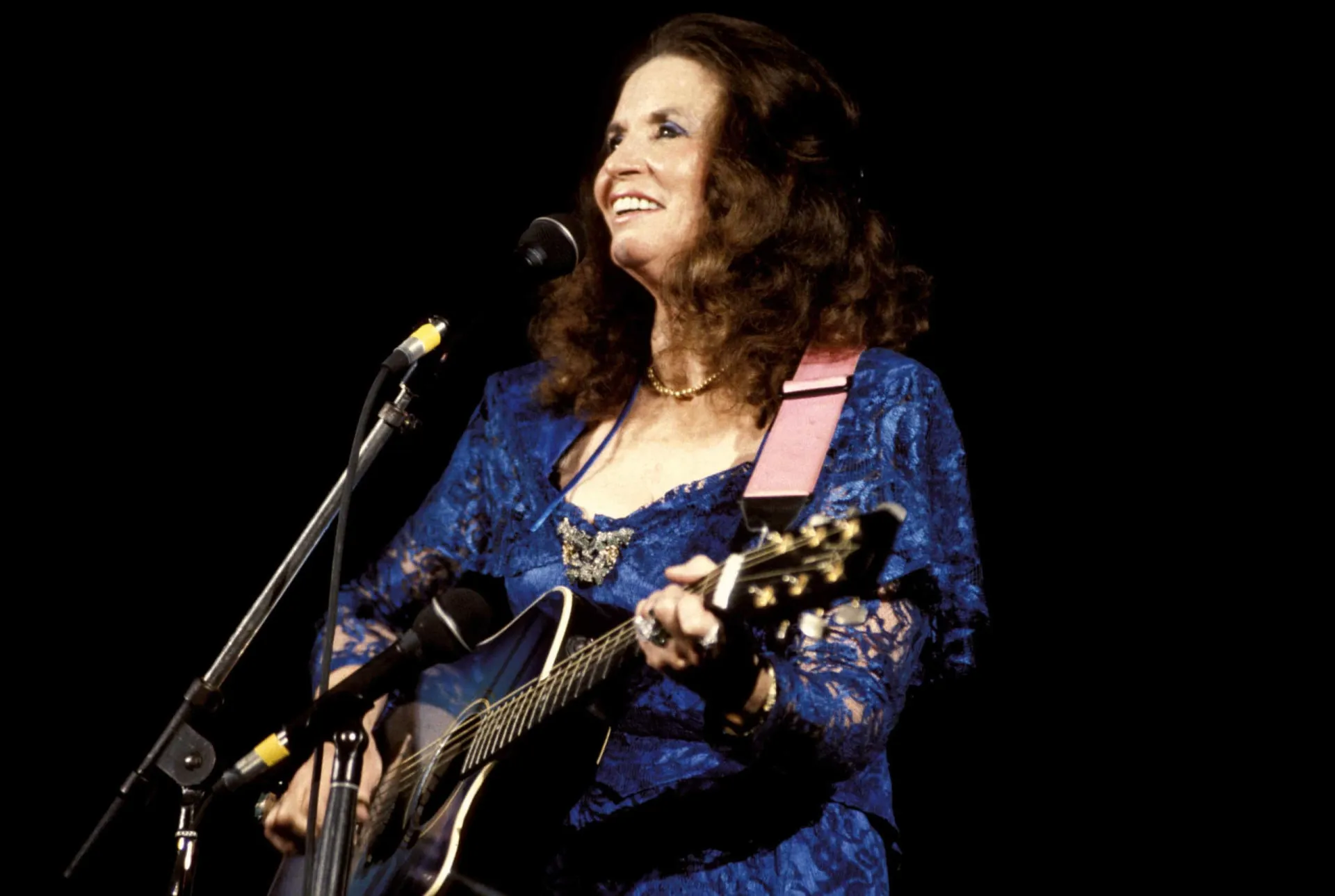 June Carter Cash sorrindo, uma imagem que captura sua alegria e espírito vibrante.