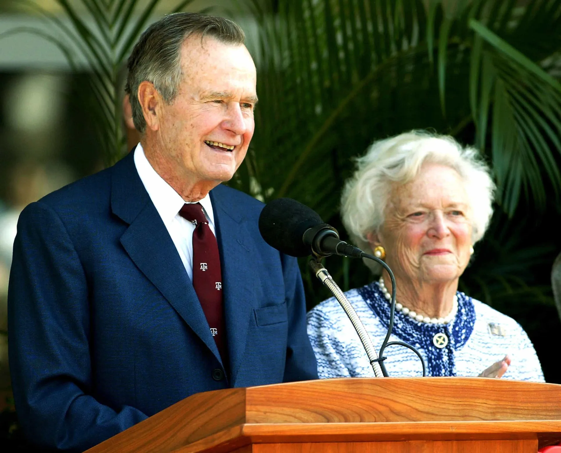 George H.W. Bush e Barbara Bush de mãos dadas, sorrindo, em um retrato de sua longa vida juntos.