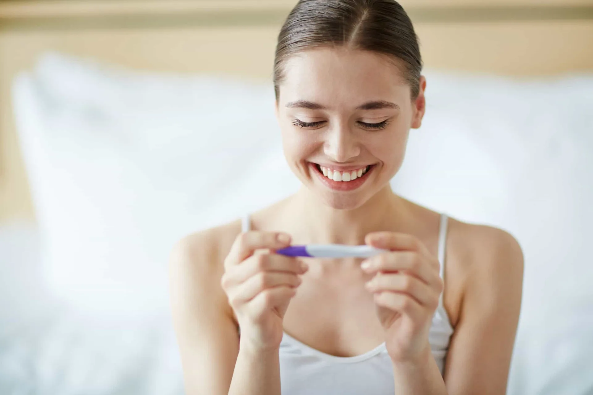 Mulher grávida sorrindo e segurando sua barriga com carinho.