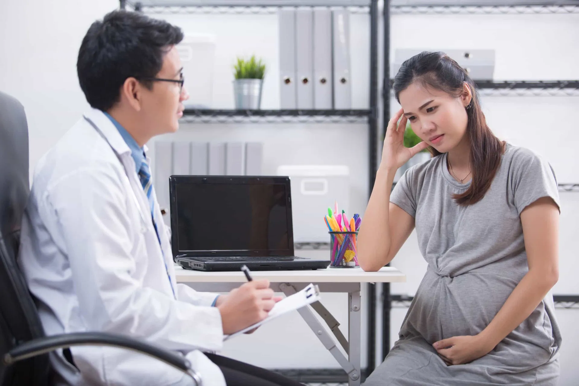 Médica conversando com paciente grávida sobre uma caixa de remédio.