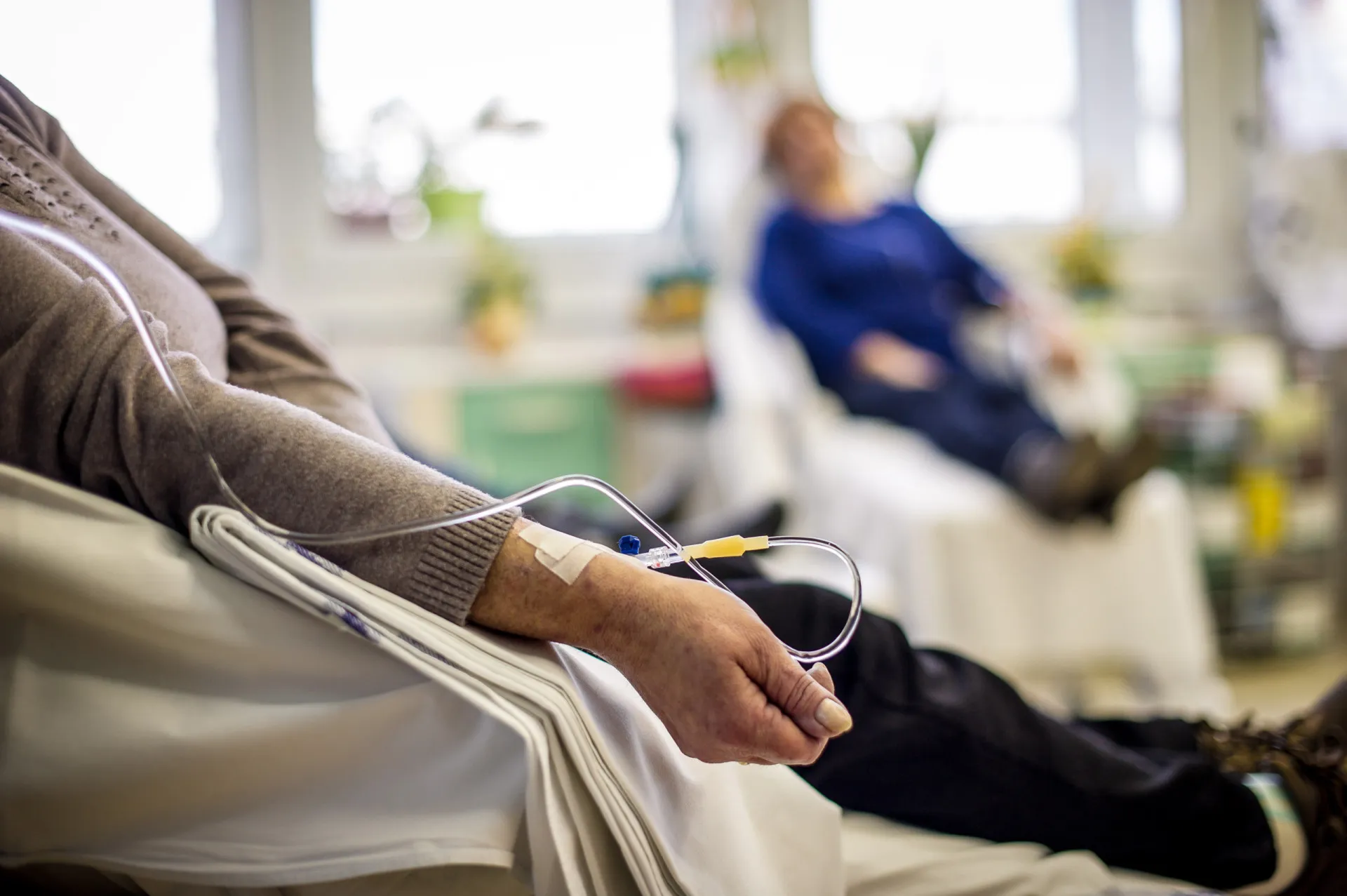 Paciente com câncer recebendo apoio de um profissional de saúde em um ambiente hospitalar.