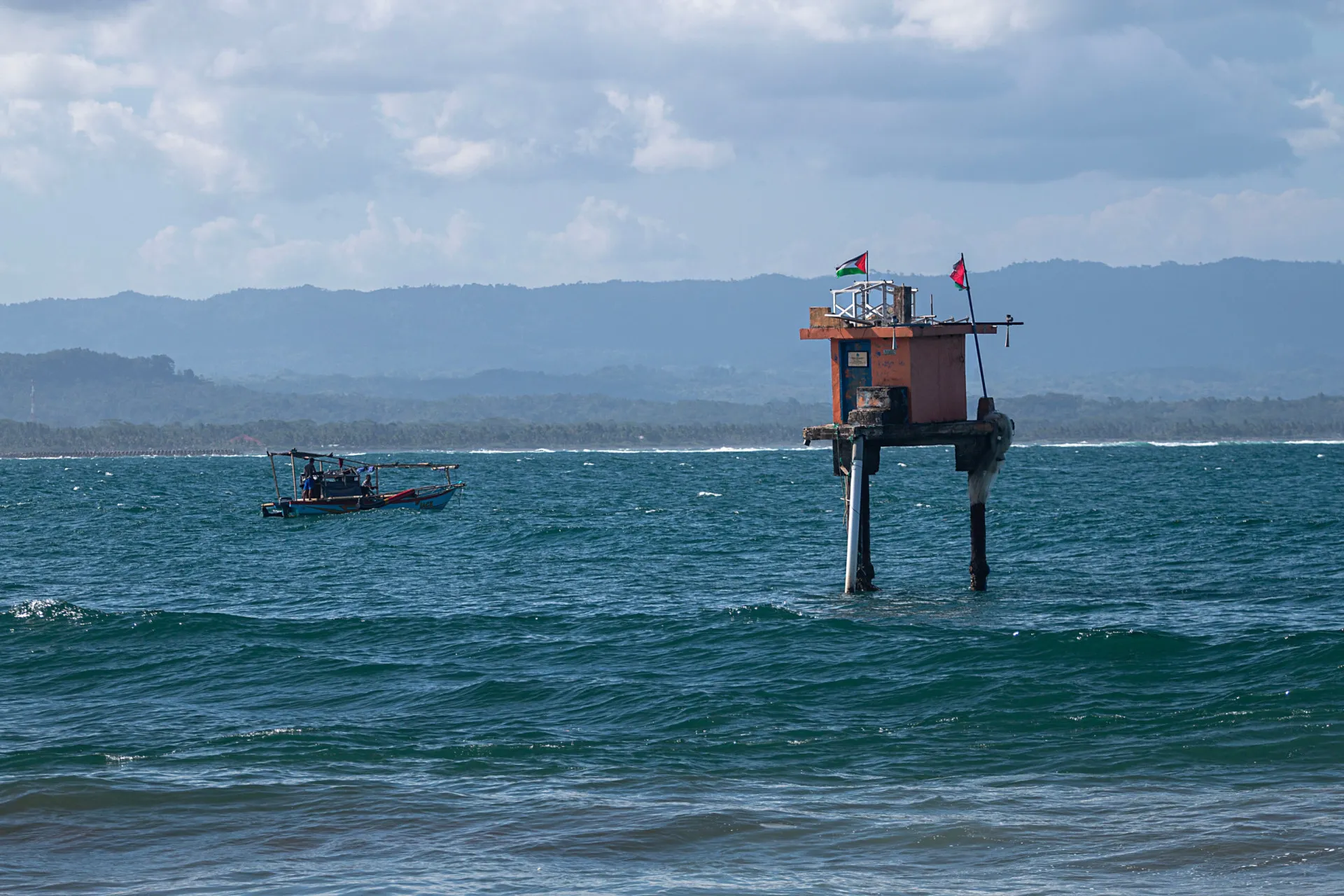 Sinal de perigo de tsunami em uma praia, com a instrução de ficar longe da área.