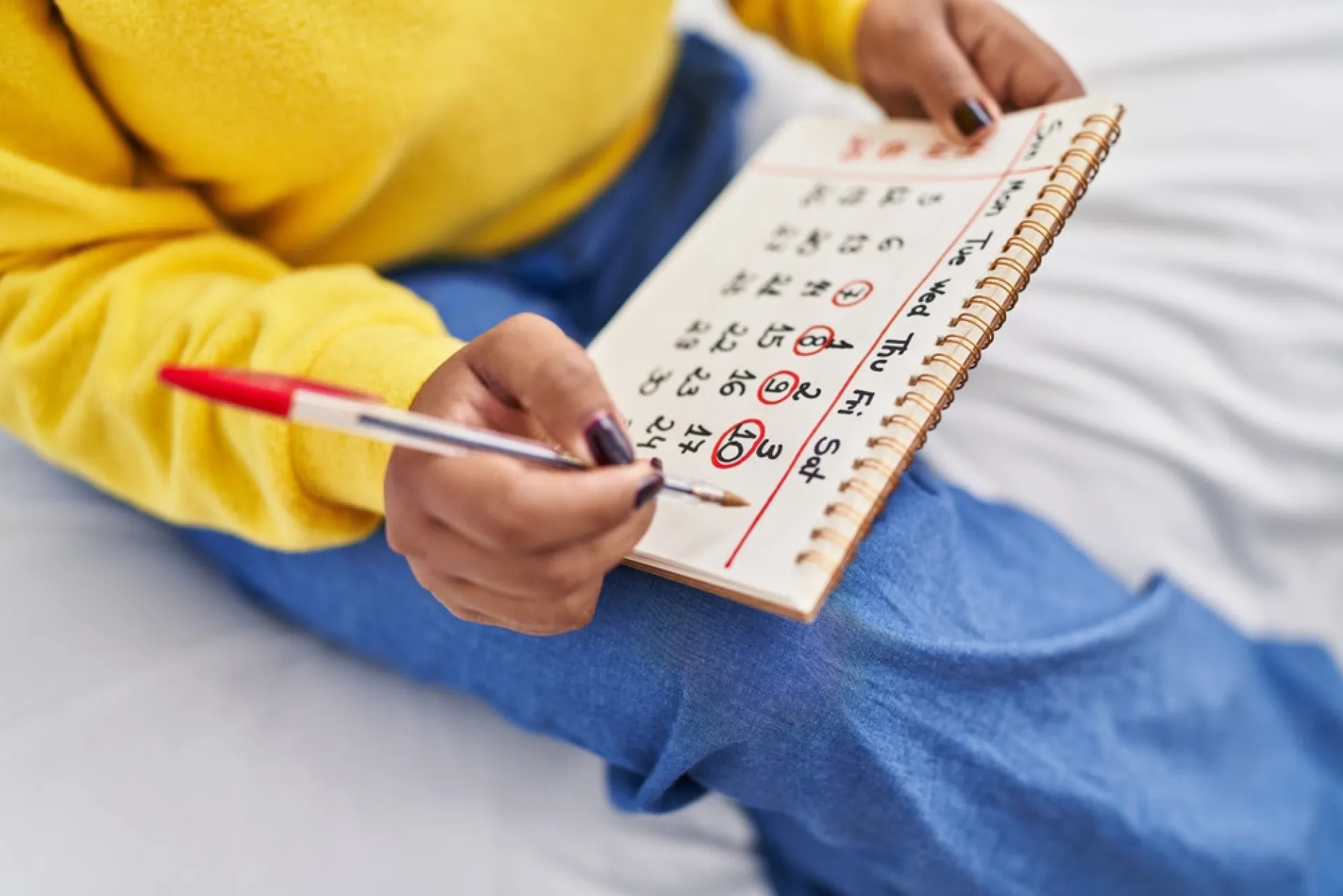 Mulher escrevendo em um diário ou calendário, anotando informações sobre seu ciclo menstrual.