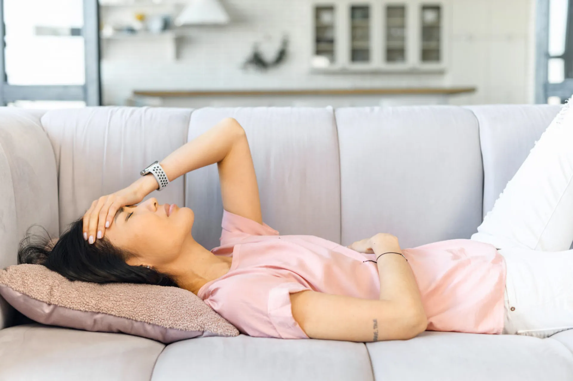 Mulher na faixa dos 30 ou 40 anos olhando pela janela, em um momento de introspecção.