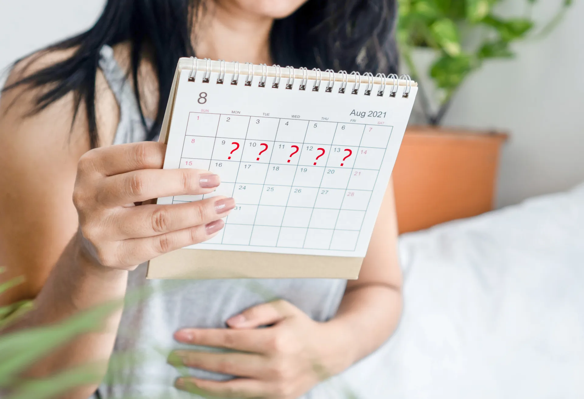Mulher olhando preocupada para um absorvente, simbolizando a preocupação com o fluxo menstrual intenso.