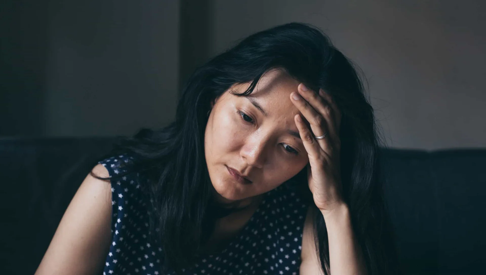 Mulher bocejando no trabalho, com papéis e um laptop à sua frente, mostrando dificuldade de concentração.