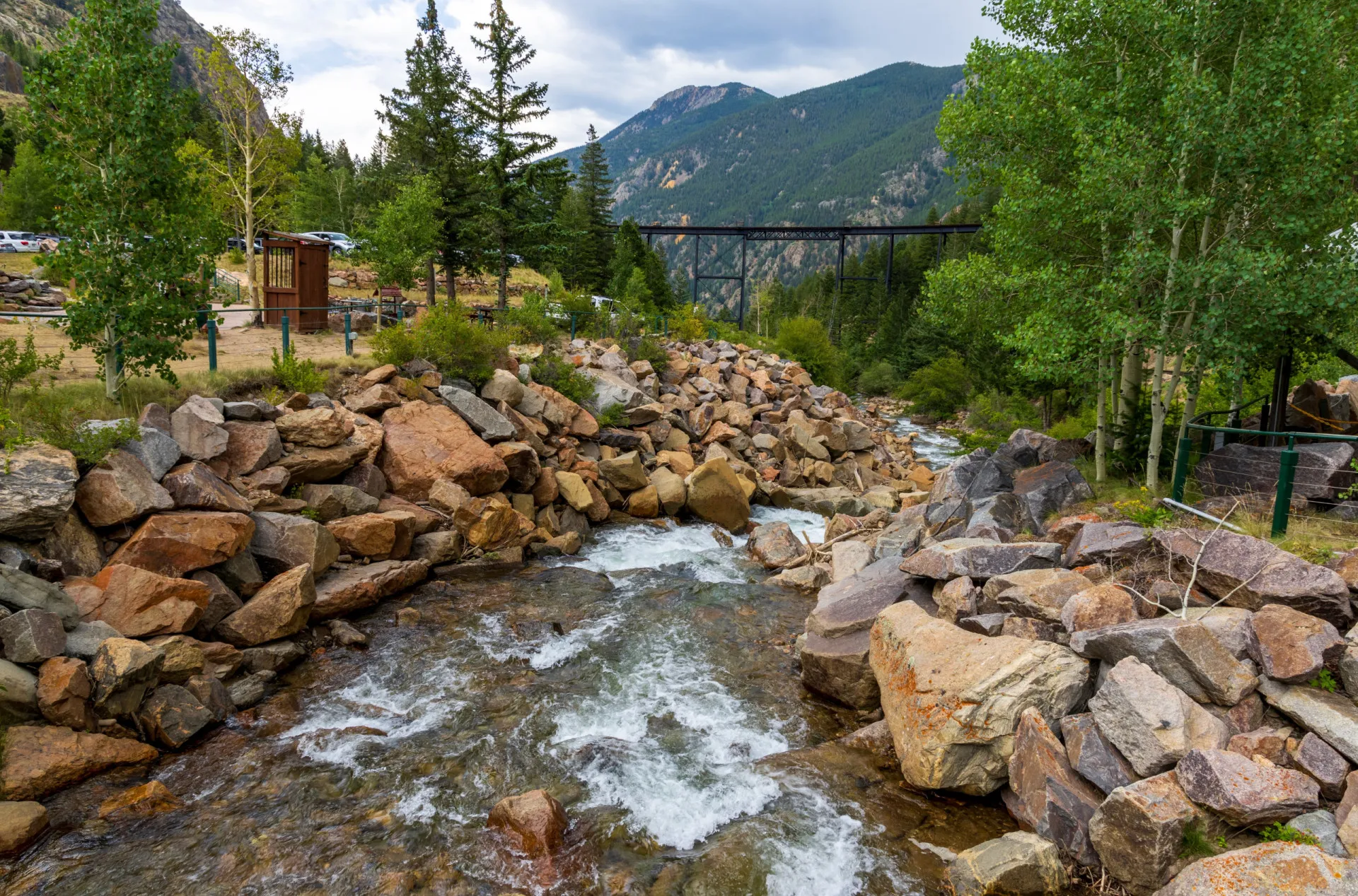 O riacho Clear Creek no Colorado, com águas correndo sobre rochas e vegetação nas margens.