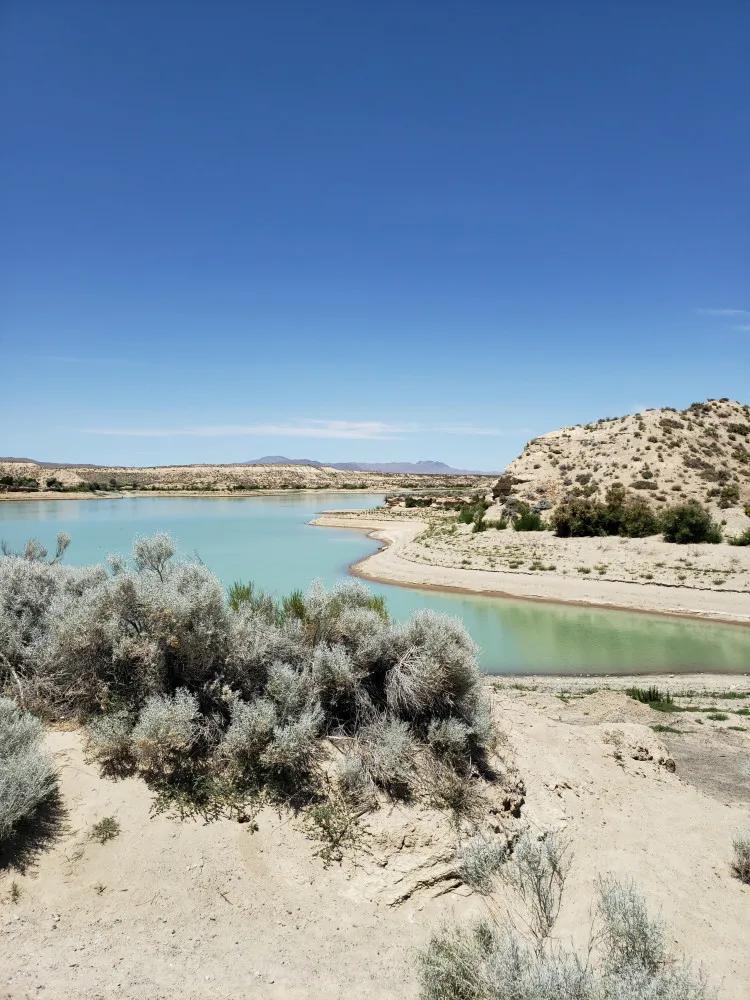 Paisagem desértica de Nevada perto do reservatório de Rye Patch, com montanhas ao fundo.