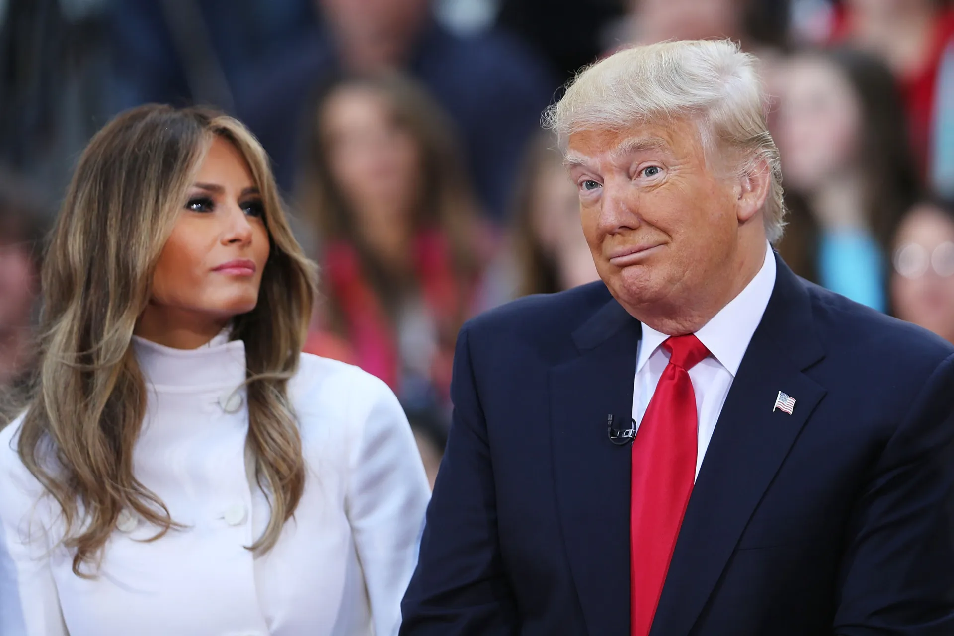 Donald e Melania Trump acenando, lado a lado, em um evento público.