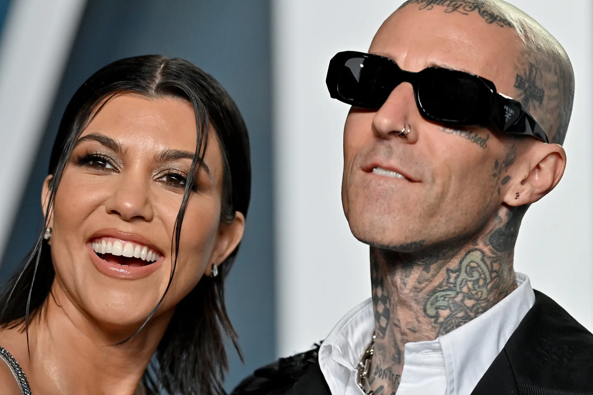 Kourtney Kardashian e o baterista Travis Barker em um tapete vermelho, com um visual ousado.