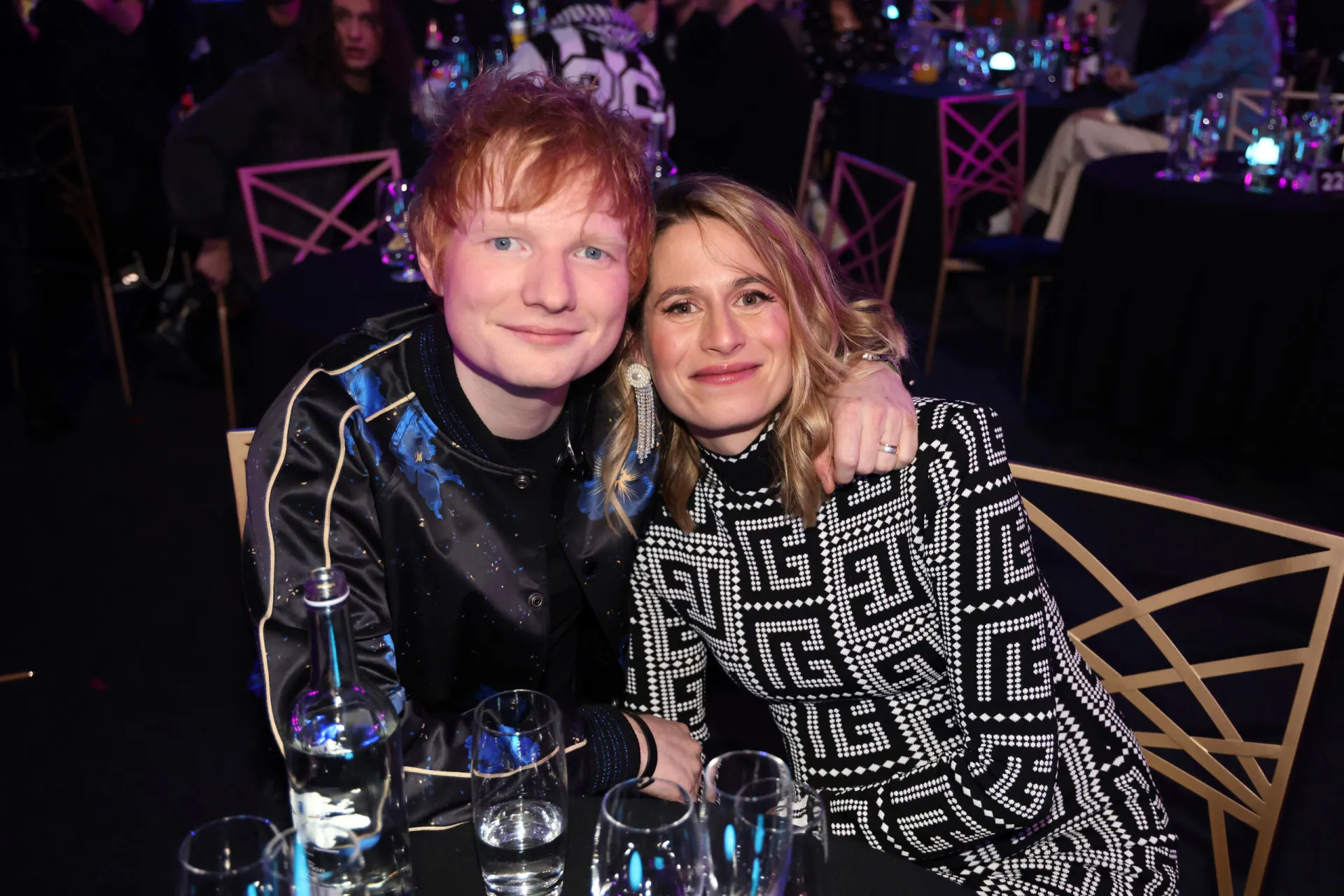 O cantor Ed Sheeran e sua esposa Cherry Seaborn em um evento, olhando um para o outro.