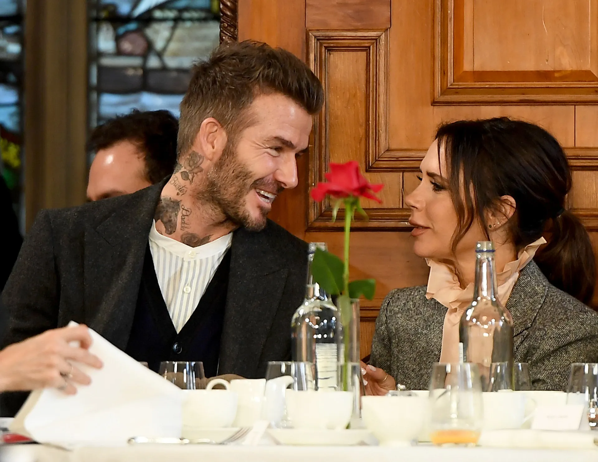 O casal Beckham em um momento mais descontraído, sorrindo para a câmera.