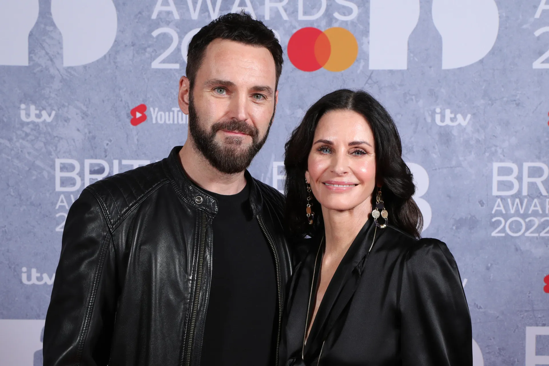 A atriz Courteney Cox e o músico Johnny McDaid abraçados em um evento.