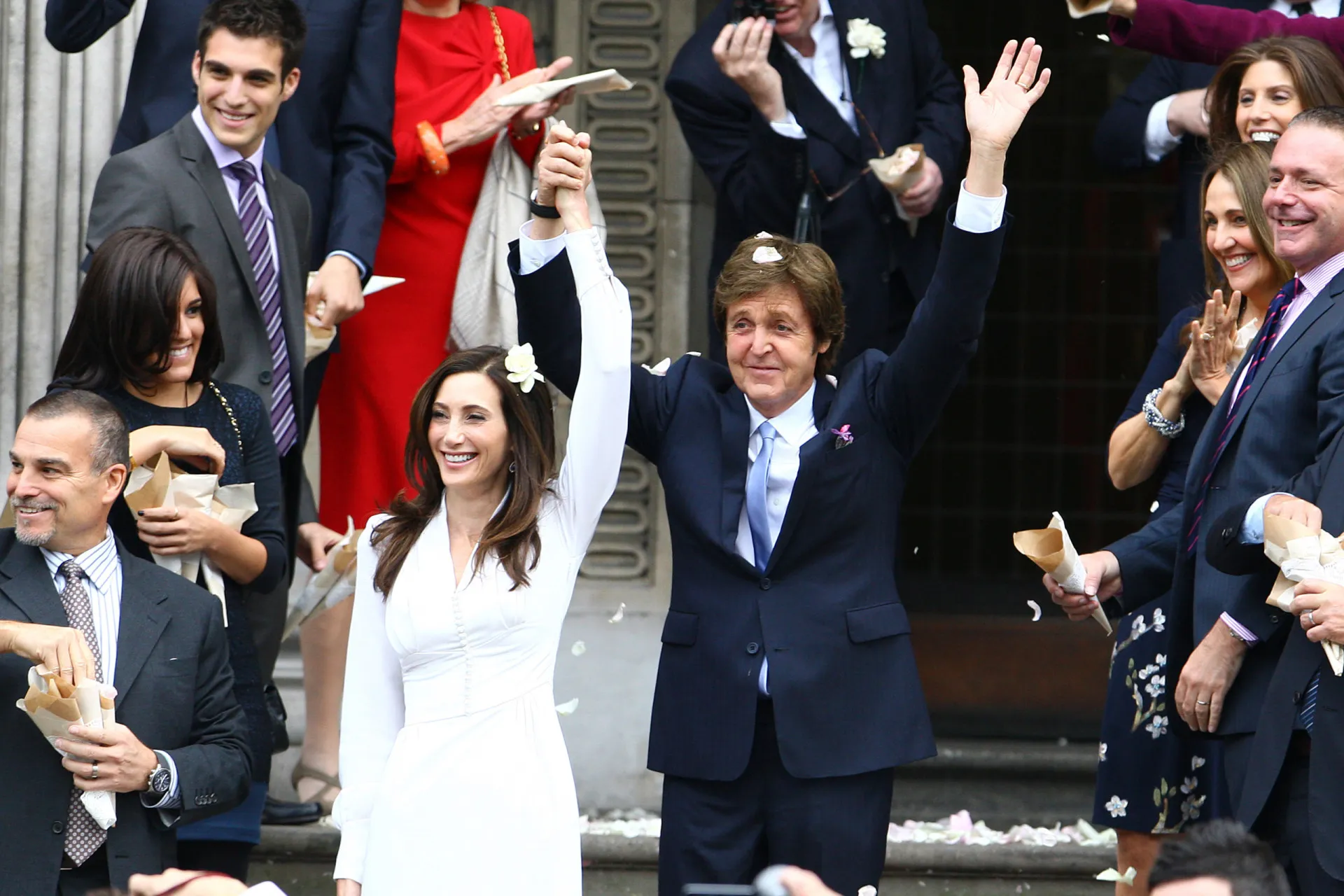 Paul McCartney e Nancy Shevell de braços dados, caminhando e sorrindo.