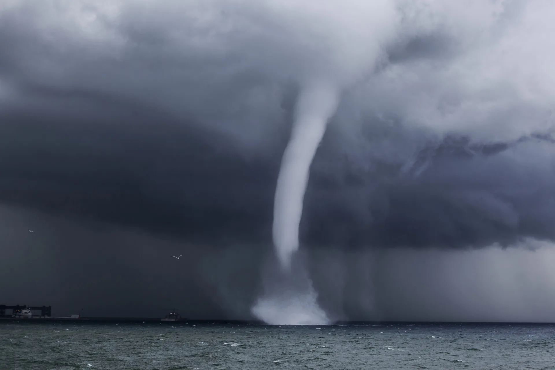 Vários meteorologistas em uma sala de controle, olhando para telas com mapas meteorológicos diferentes e desconectados.
