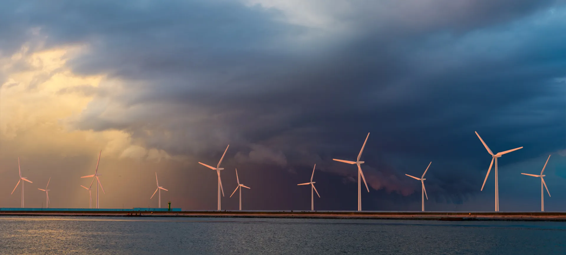 Parque eólico offshore com céu tempestuoso, representando o risco que trombas d'água representam para a infraestrutura.