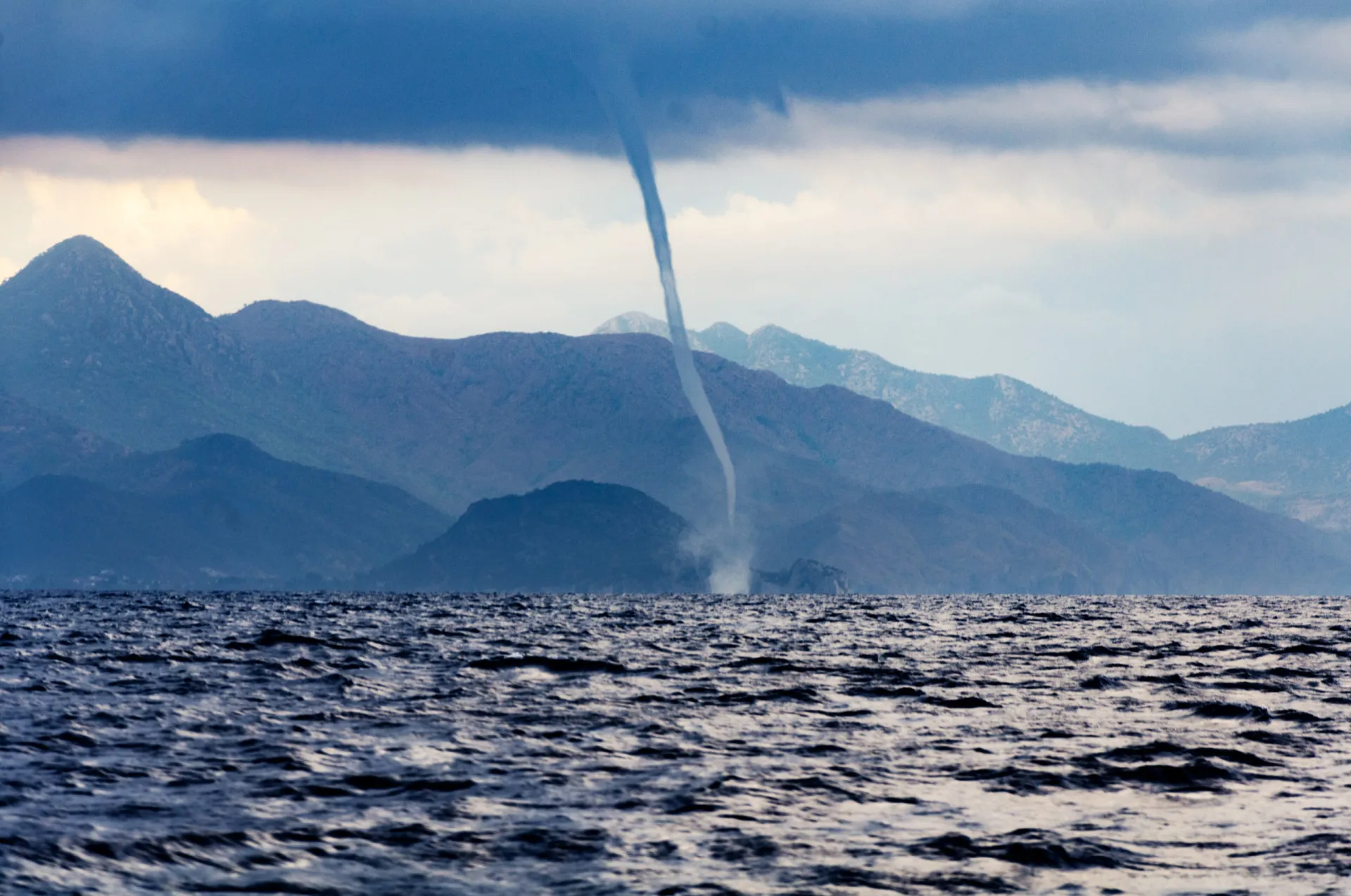 Uma tromba d'água escura e ameaçadora, com a aparência de um tornado sobre o mar.