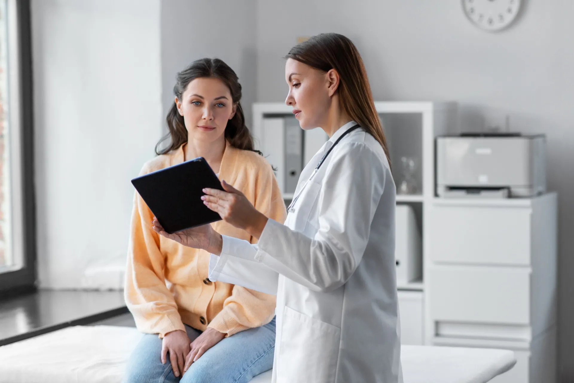 Médico conversando com uma paciente em um consultório, em atitude de escuta e acolhimento.