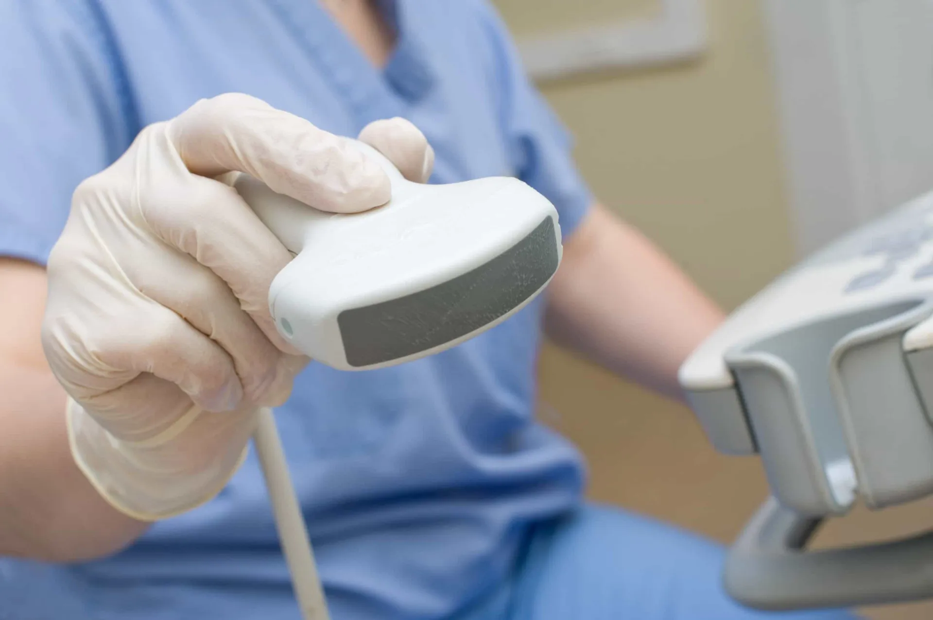 Médico realizando um exame de ultrassom em uma paciente, com a tela do aparelho em destaque.