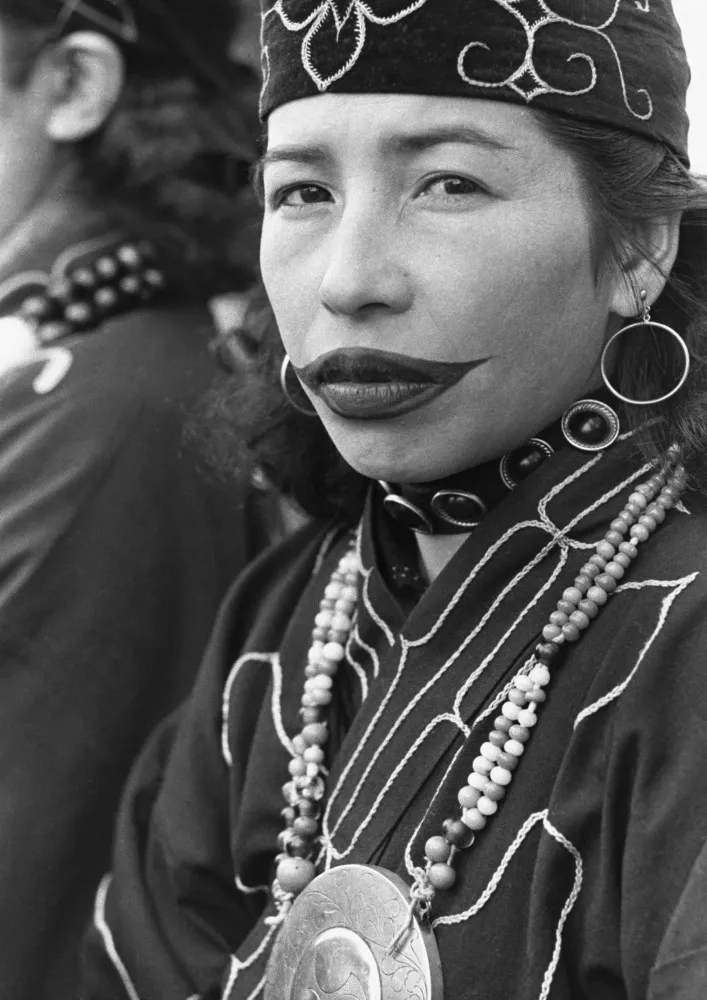Mulher Ainu com tatuagens tradicionais nos lábios e um grande brinco de argola.