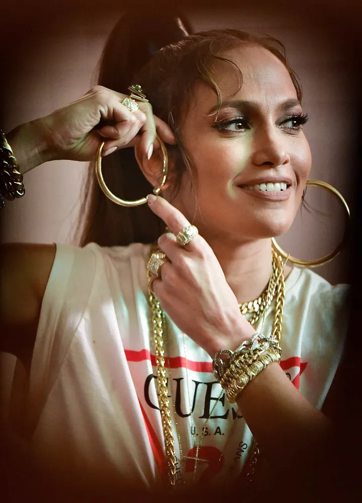 Jennifer Lopez usando seus característicos brincos de argola grandes, um marco de seu estilo.