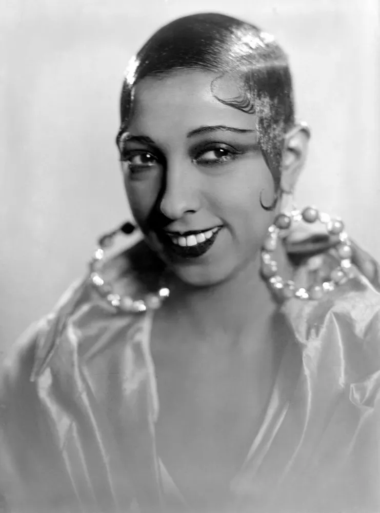 Josephine Baker posando com um olhar confiante e usando brincos de argola grandes e ornamentados.