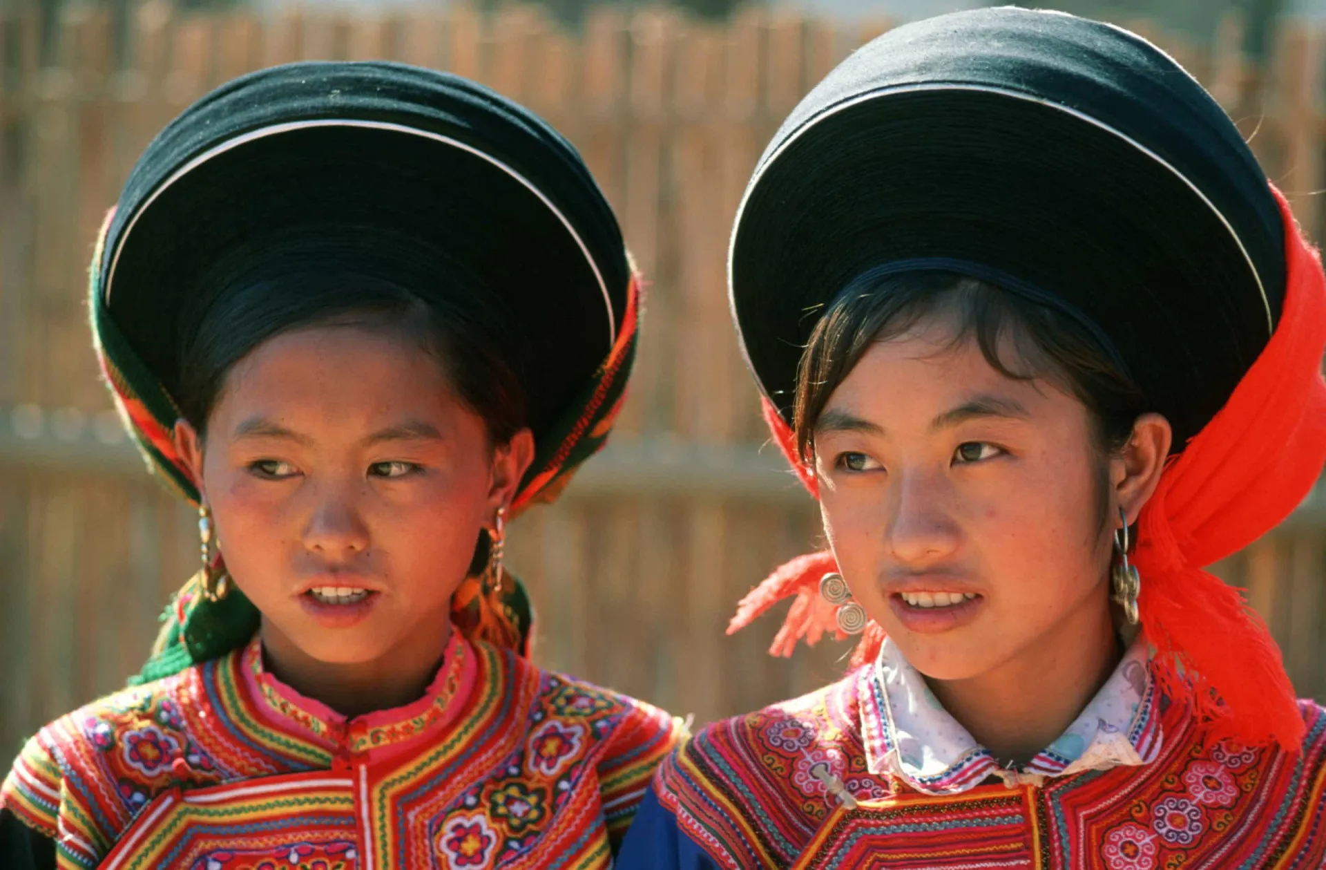 Mulher do povo Hmong do Vietnã usando roupas tradicionais coloridas e grandes brincos.