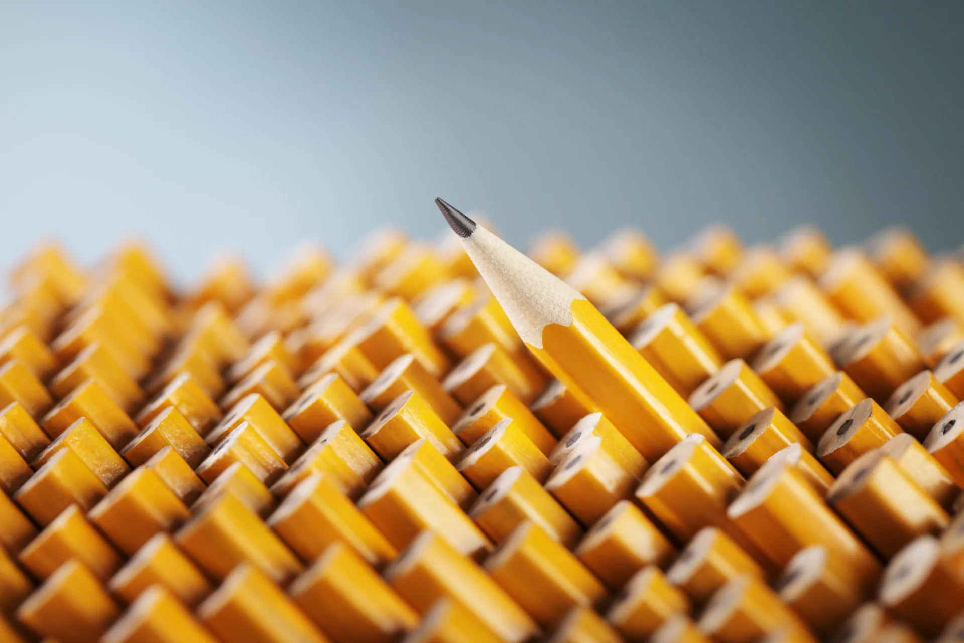 Detalhe da ponta de um lápis amarelo sobre uma folha de papel branco.