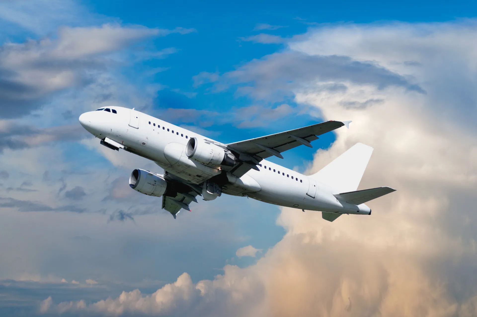 Um avião comercial branco decolando contra um céu azul claro.