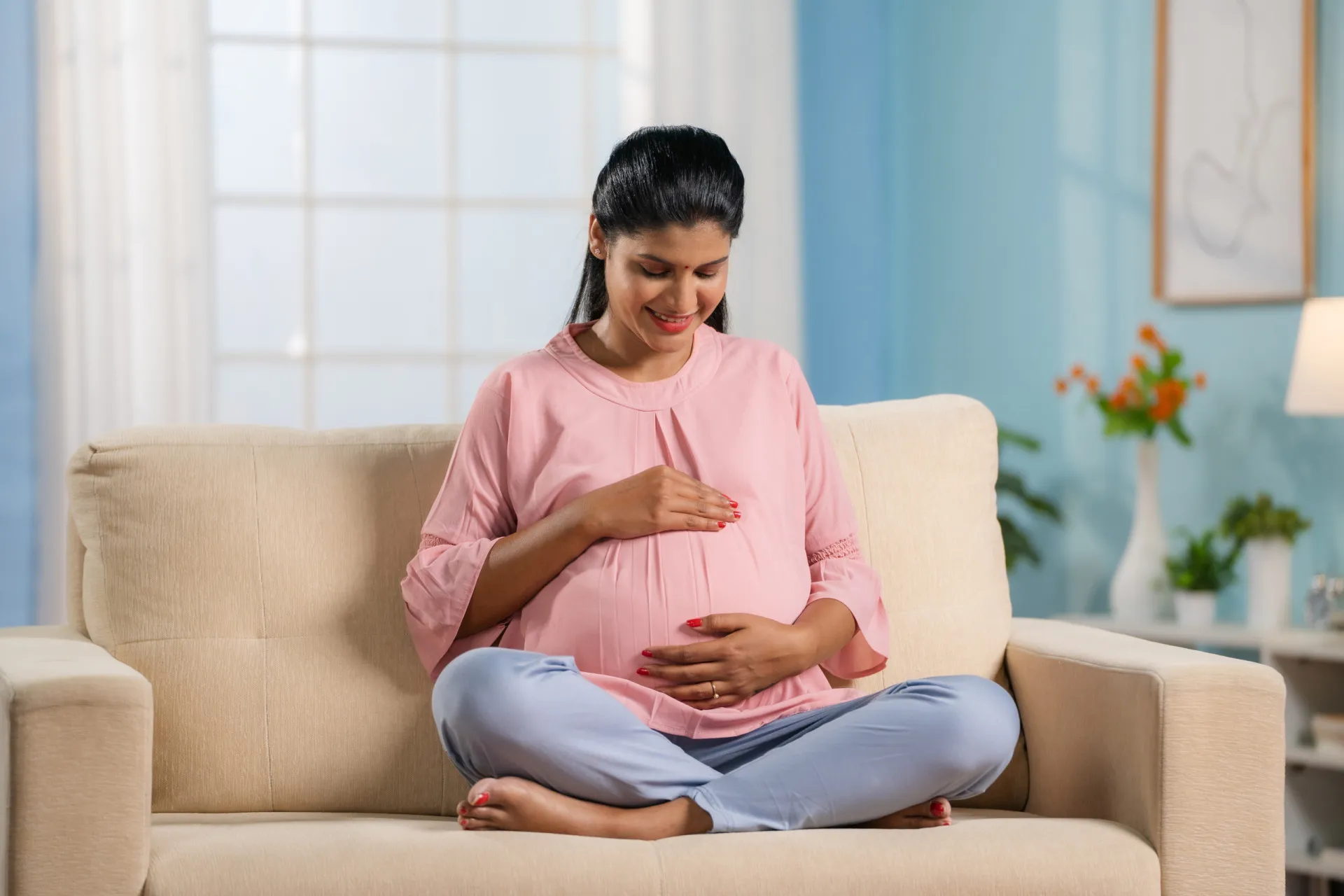 Mulher grávida com a mão na barriga, sentindo os sintomas normais da gestação.