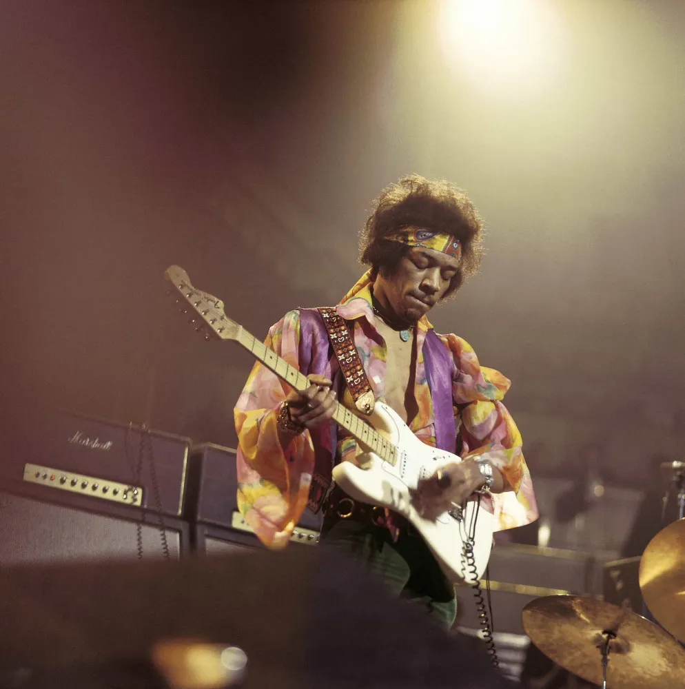 O lendário guitarrista Jimi Hendrix tocando sua guitarra com uma expressão concentrada e apaixonada.