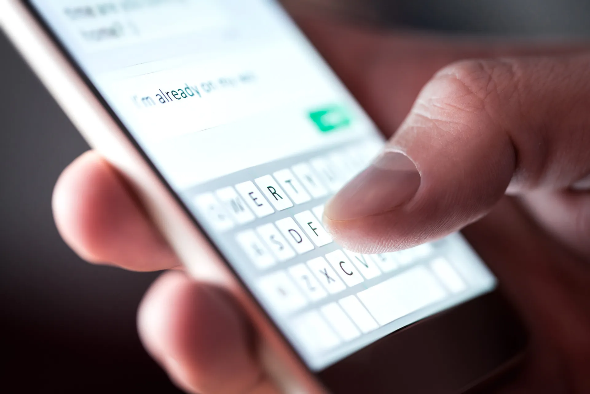 Um dedo digitando em um teclado de smartphone, com a barra de sugestão de palavras aparecendo logo acima.