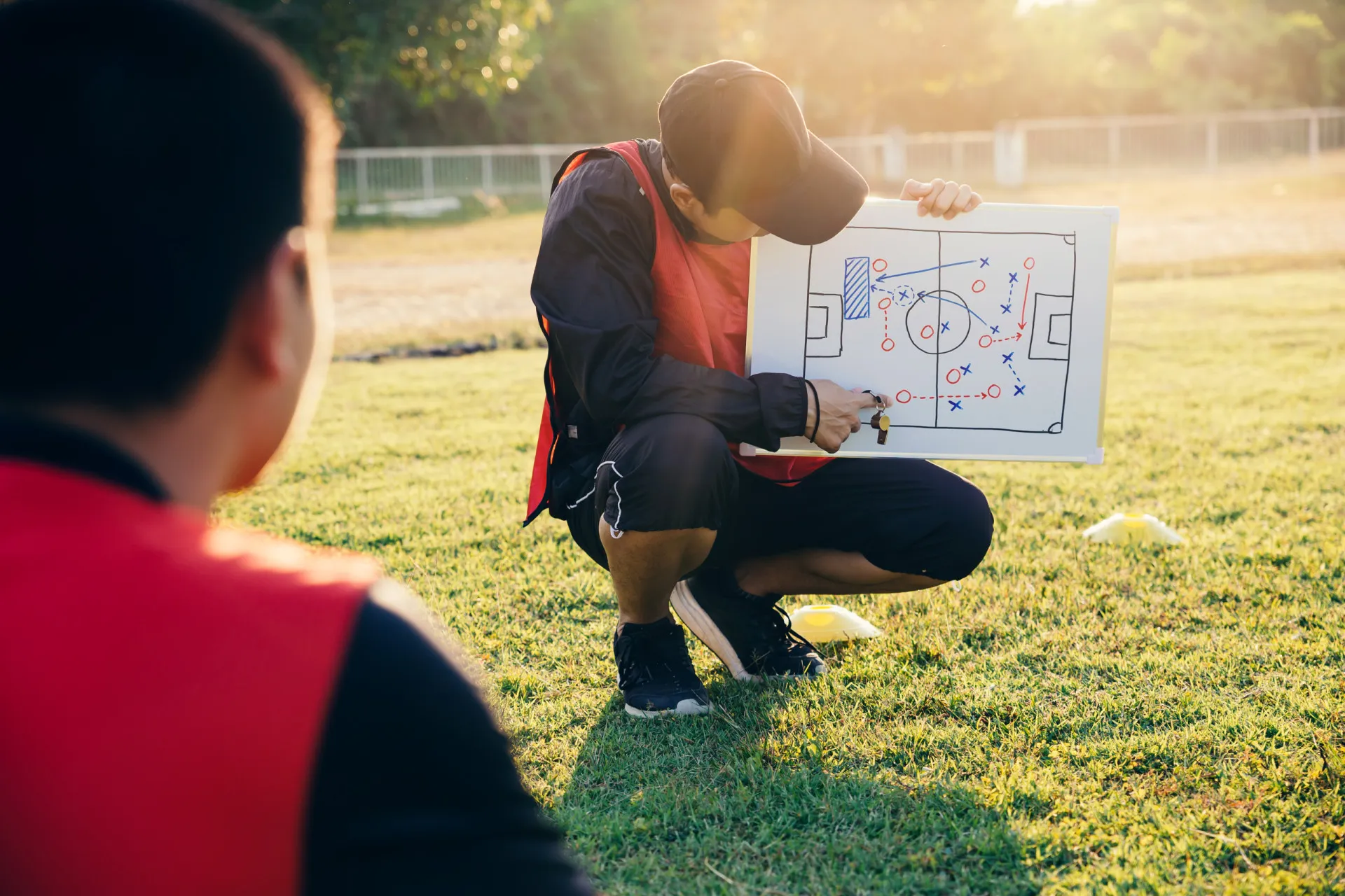 Um técnico de futebol em frente a uma prancheta tática, planejando a estratégia do jogo com seus jogadores.