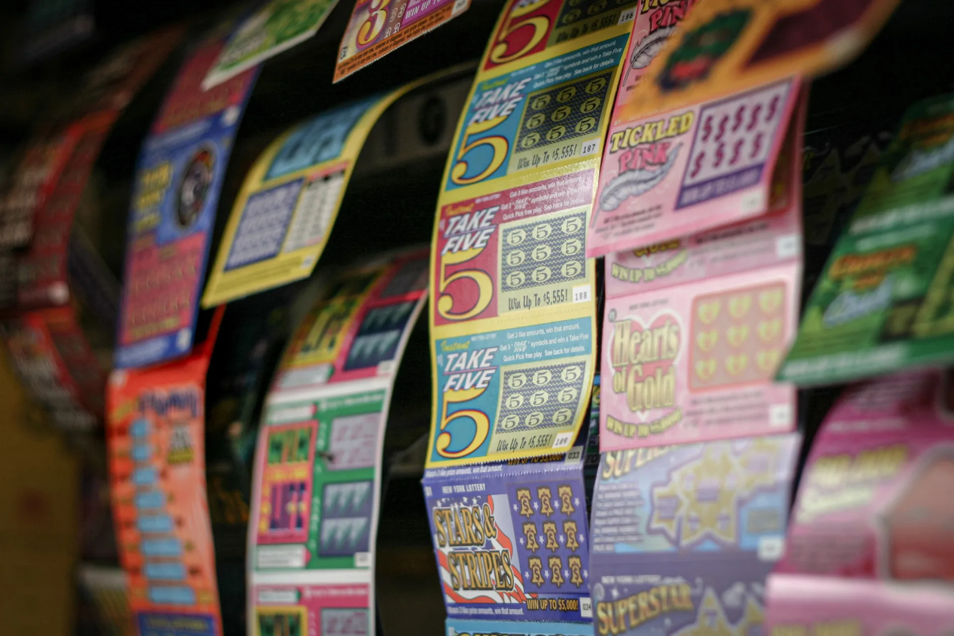 Uma mão segurando um bilhete de loteria com bolas numeradas ao fundo, representando a esperança de ganhar o grande prêmio.