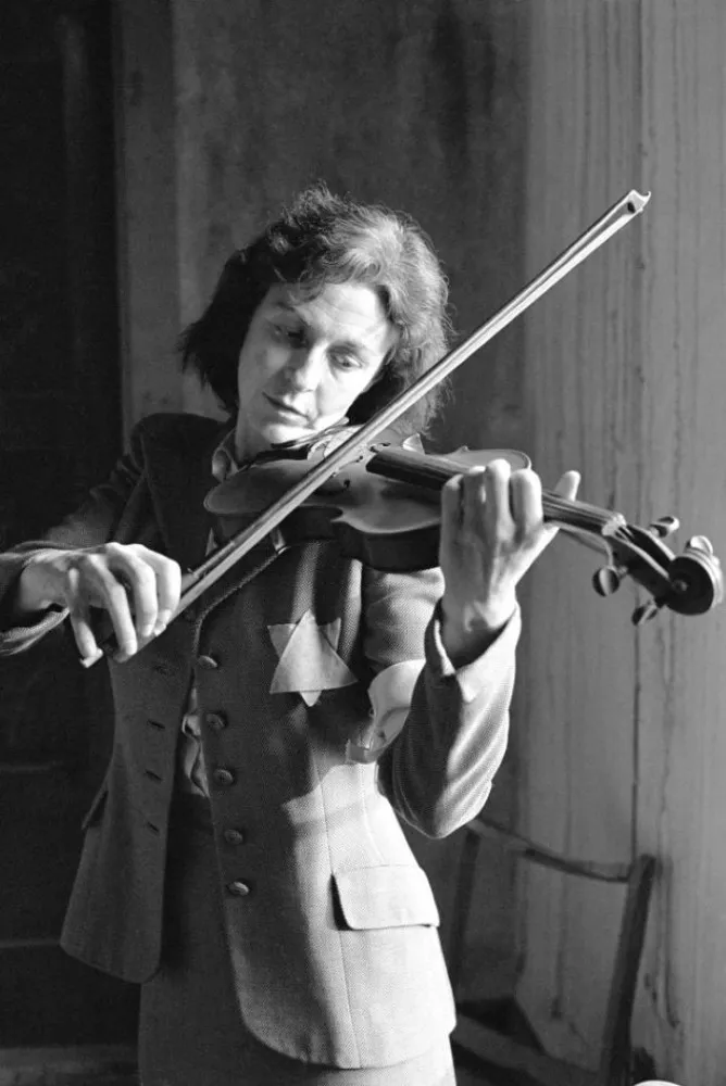 Mulheres da orquestra de Auschwitz tocando seus instrumentos com expressões concentradas.
