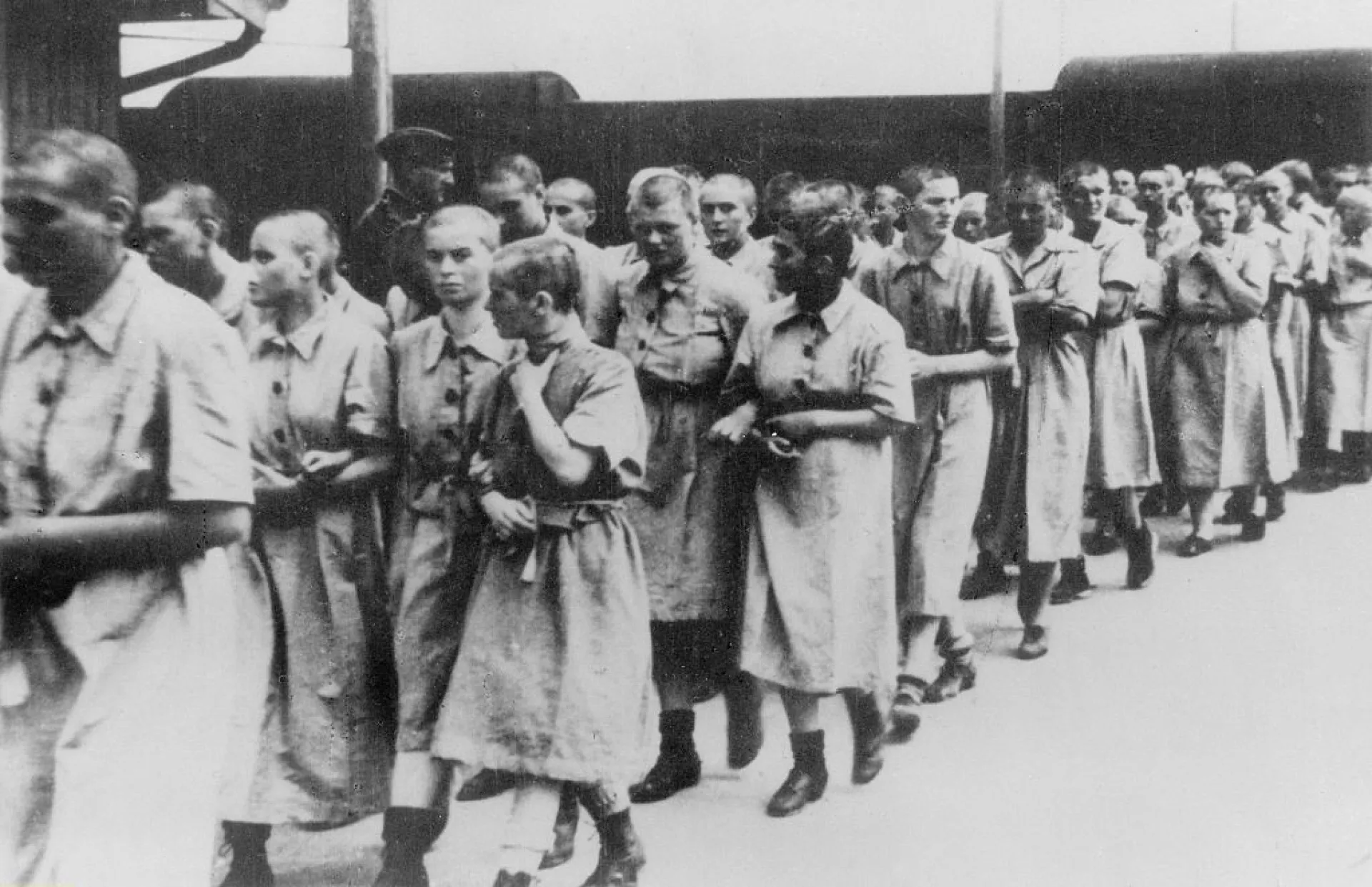 Duas mulheres prisioneiras em Auschwitz conversando em segredo, representando a conversa que salvou Anita.