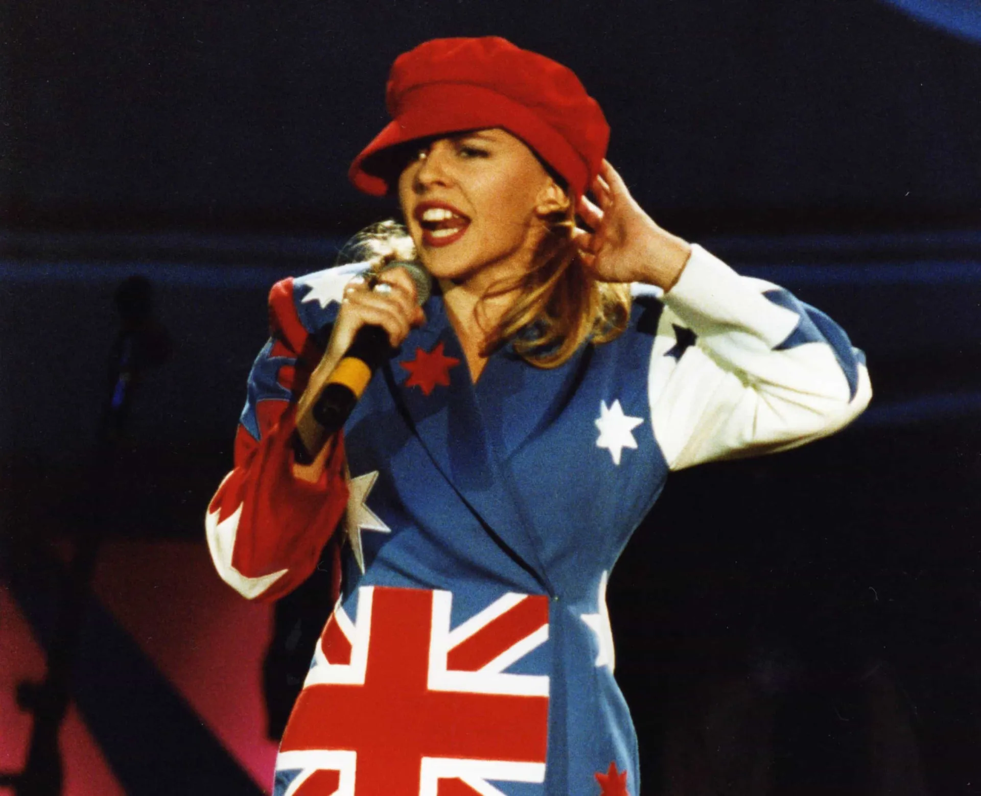 A cantora Kylie Minogue com um vestido brilhante, olhando para a câmera.