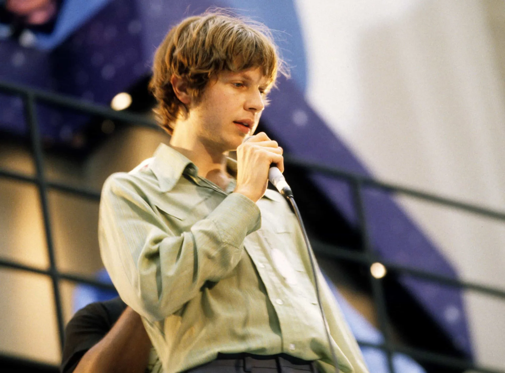 O músico Beck com um chapéu, em seu estilo alternativo característico dos anos 90.
