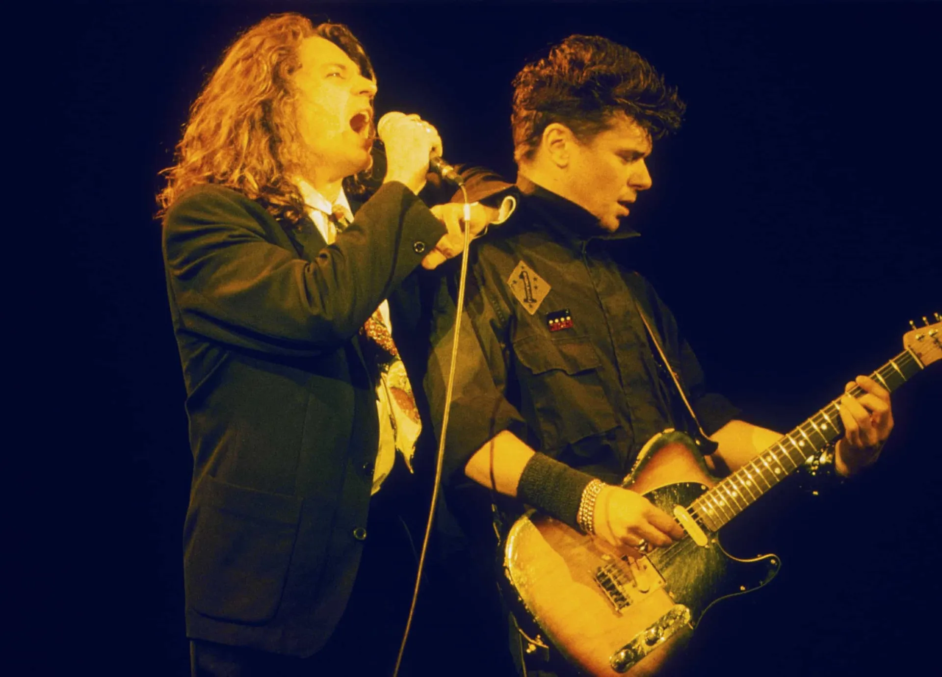 Michael Hutchence, vocalista do INXS, com seu visual icônico e carismático no palco.