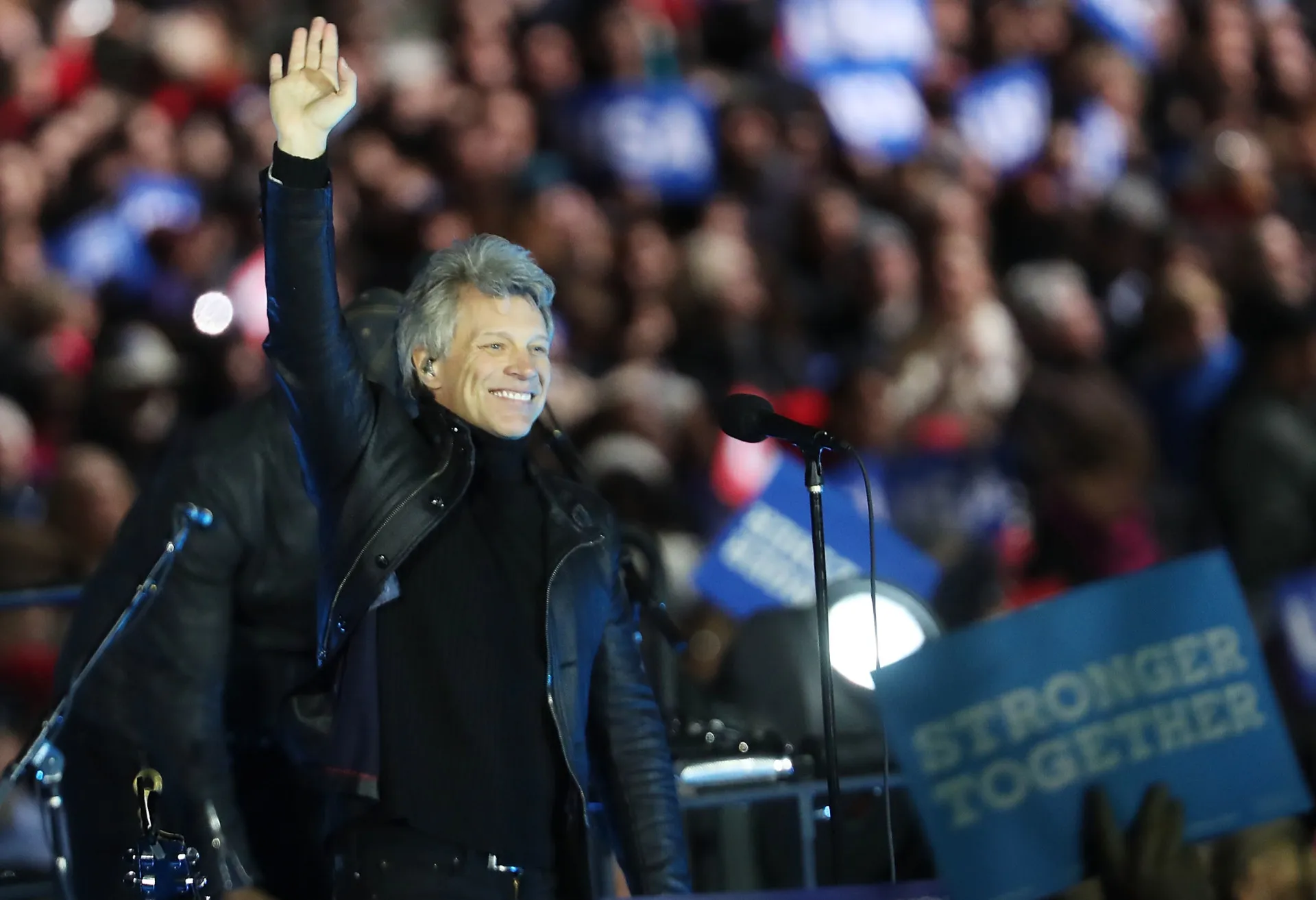 Jon Bon Jovi cantando apaixonadamente em um microfone durante um show.